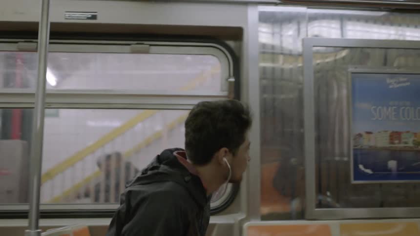 Man riding a subway and then exiting as it comes to a stop