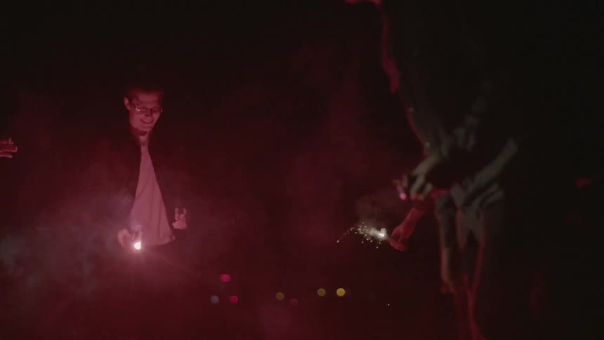 A group of people are out in the night using flares and running around