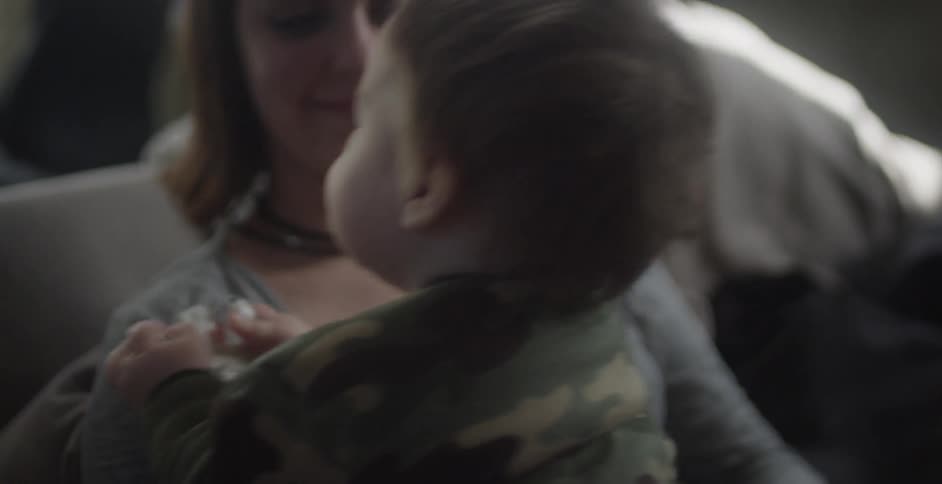 A woman is smiling as a baby bounces around on her lap