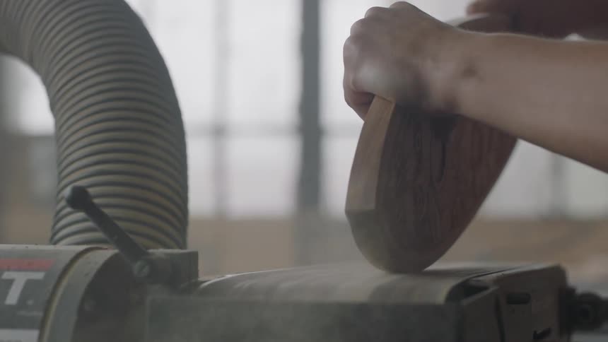 Person using sanding machine to sand a piece of wood