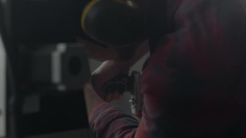 A man wearing protective ear covering uses a drill