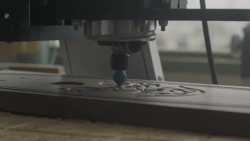 A machine is etching a design into a piece of wood
