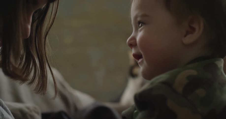 A baby smiles as he looks at a woman