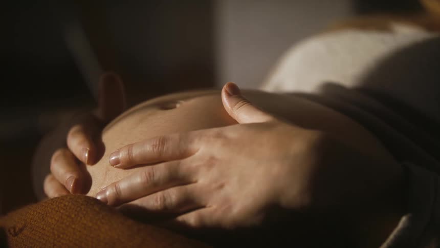 A pregnant woman touching her belly