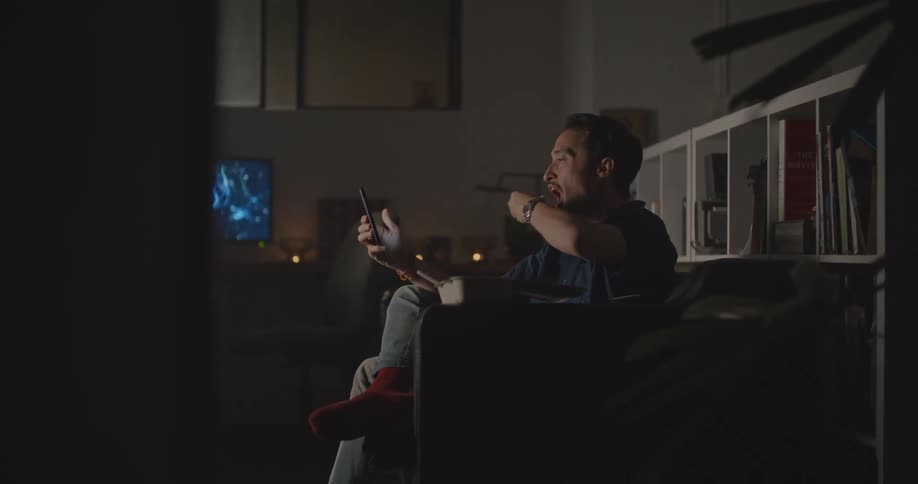 A man sitting in a room on a smart phone