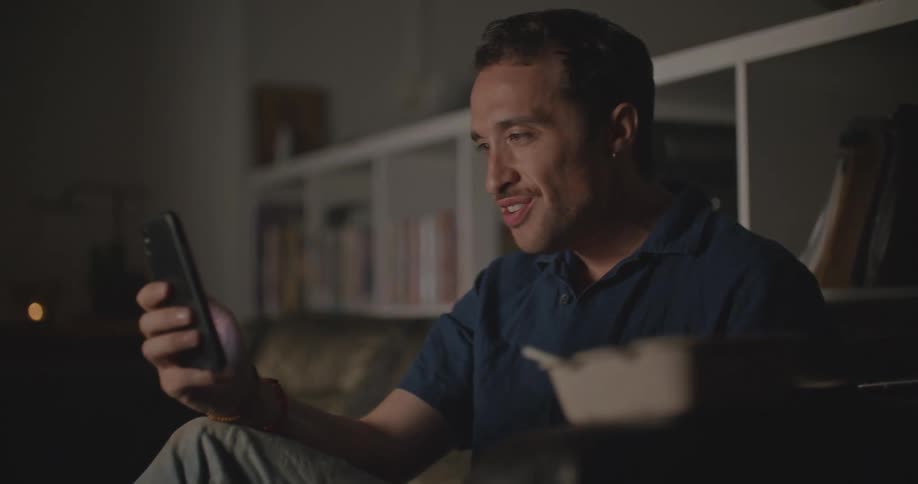 A man is using his cell phone by the couch