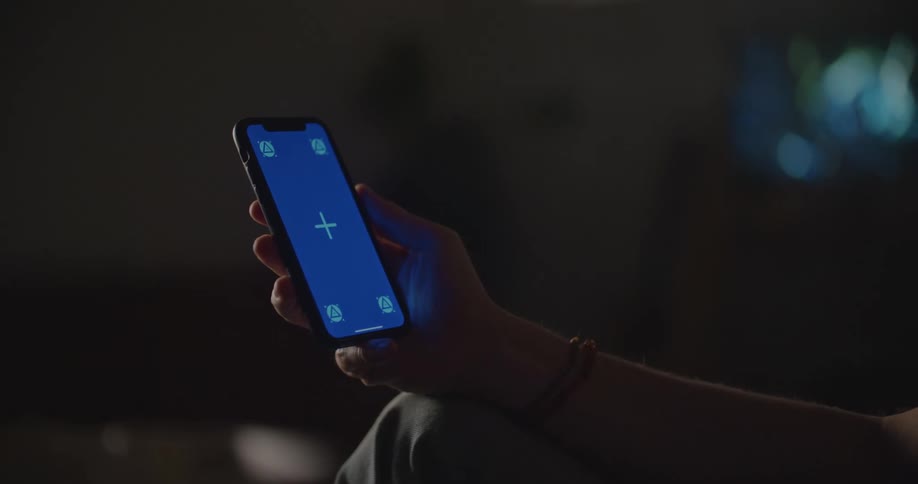 A man uses his smartphone with it propped on his leg