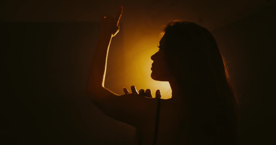 A woman dances in front of a bright light
