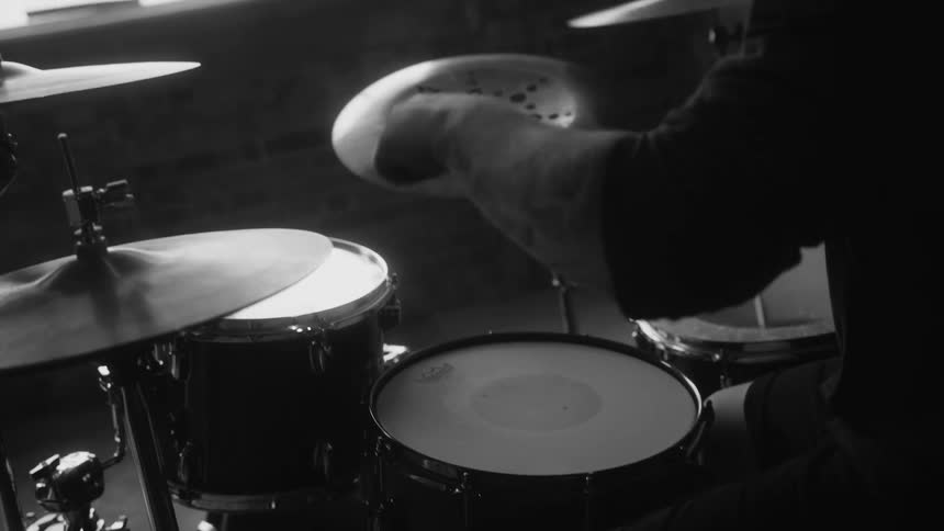 A man playing the drums in a room with a large window