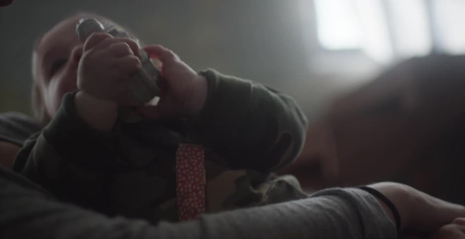 A baby plays with a toy while in a person's arms