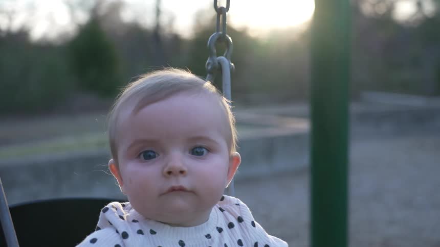 A girl swings in a baby swing in the park