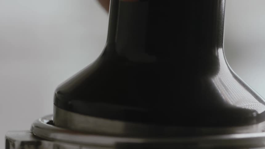 Close up of metal coffee presser pressing down coffee grounds
