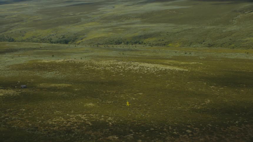 A helicopter flies over a vast grassland during the day