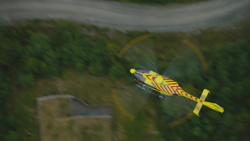 View from above a yellow and red rescue helicopter flying over land