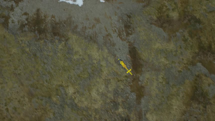 View from above a yellow and red rescue helicopter flying over land