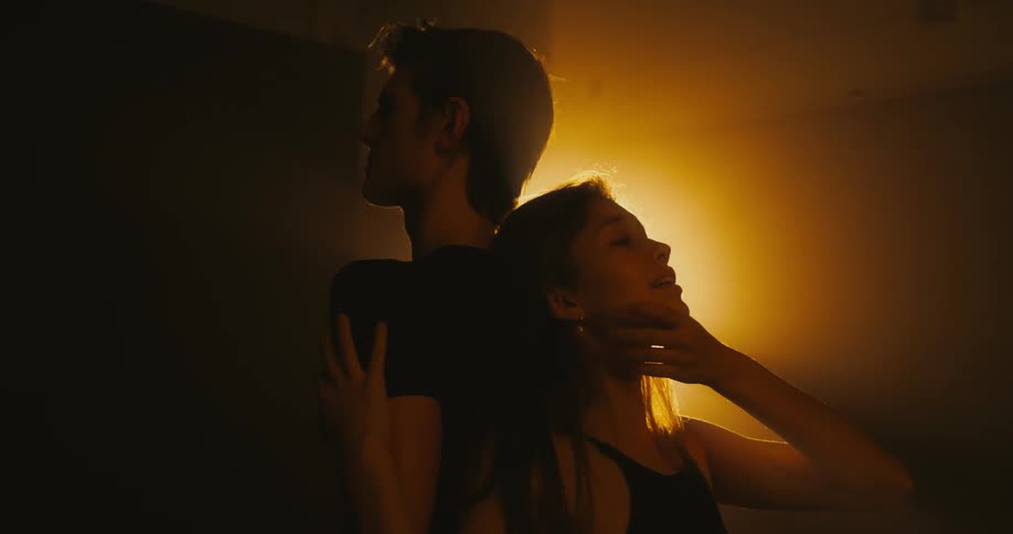 A woman touches her partners shoulder as they dance standing back to back