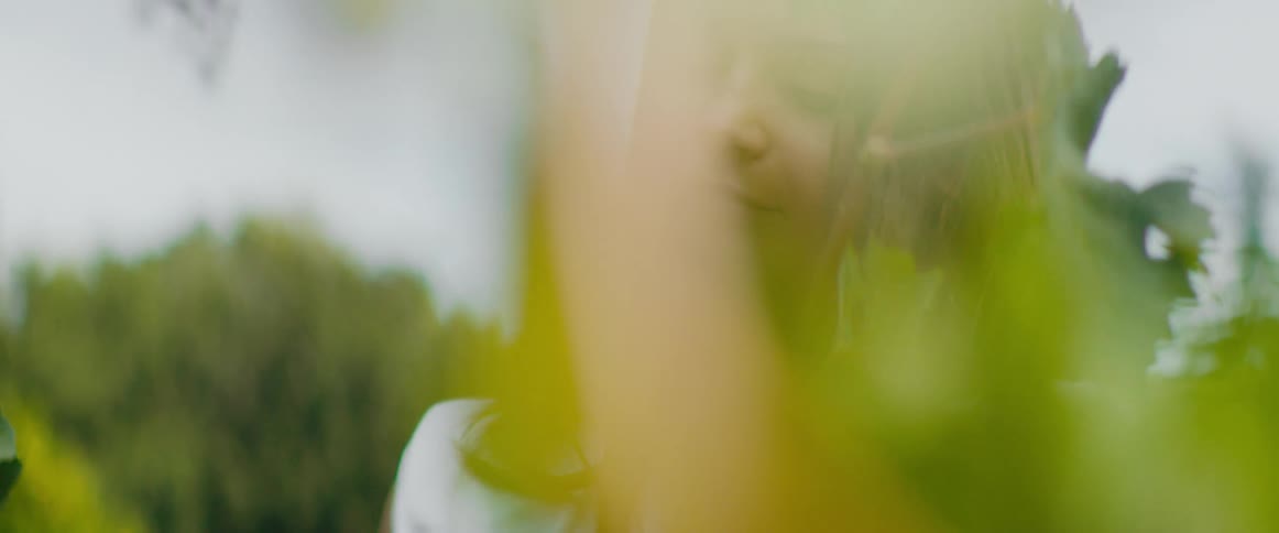 A woman stands in a garden with tall vines