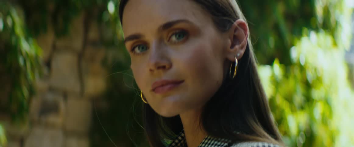 A woman standing outside turns and faces forwards and looks straight ahead