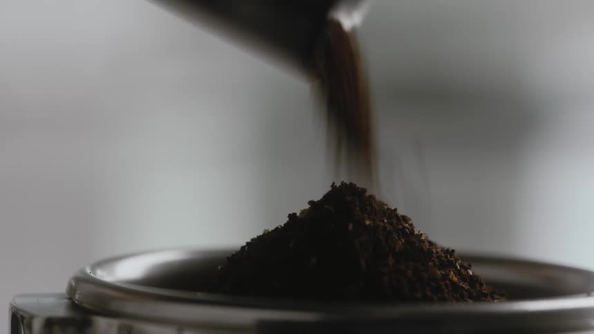 Ground coffee is poured into a chrome container