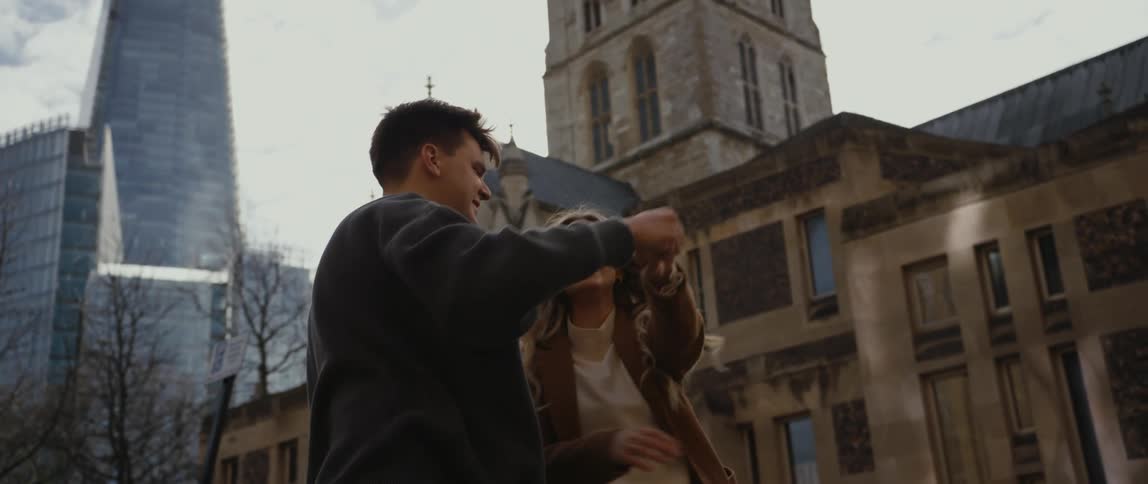 Two teenagers dance in front of a church in a city and then the boy kisses the girl