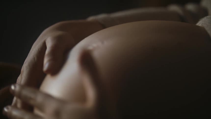 Pregnant woman wearing sweater strokes her belly
