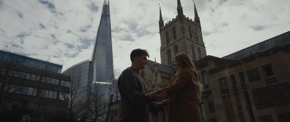 Man and woman romantically dancing together outdoors in front of a historical building in a big city