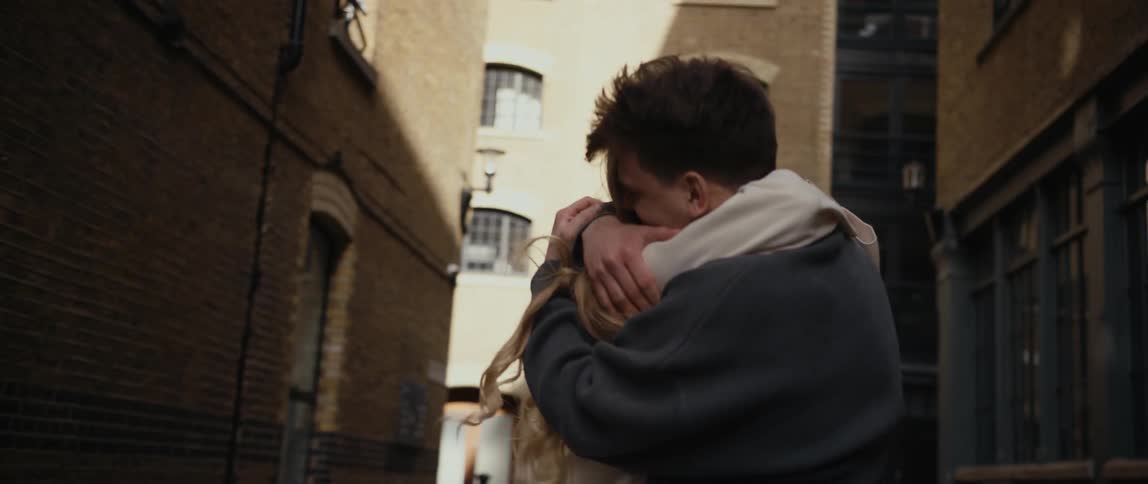 Man and woman happily hugging and kissing each other in the middle of the street on a alley of a big city