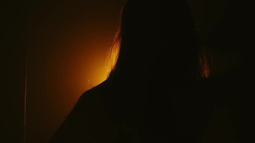 A view of a woman dancing in front of a light