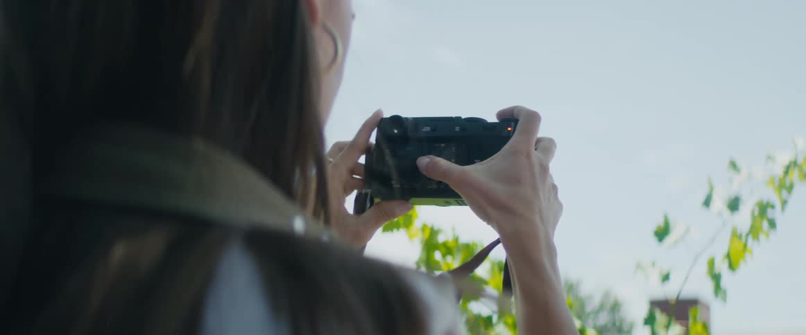 Woman taking pictures of the leaves with a photography camera at a sunny day