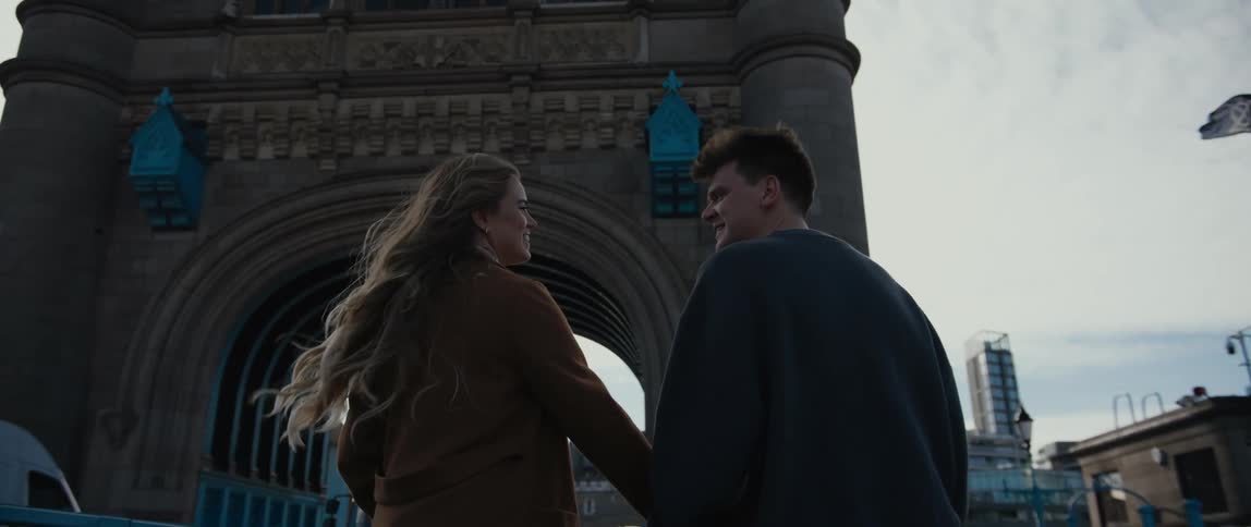 Man and woman hold hands as they walk towards a tunnel that vehicles are traveling through