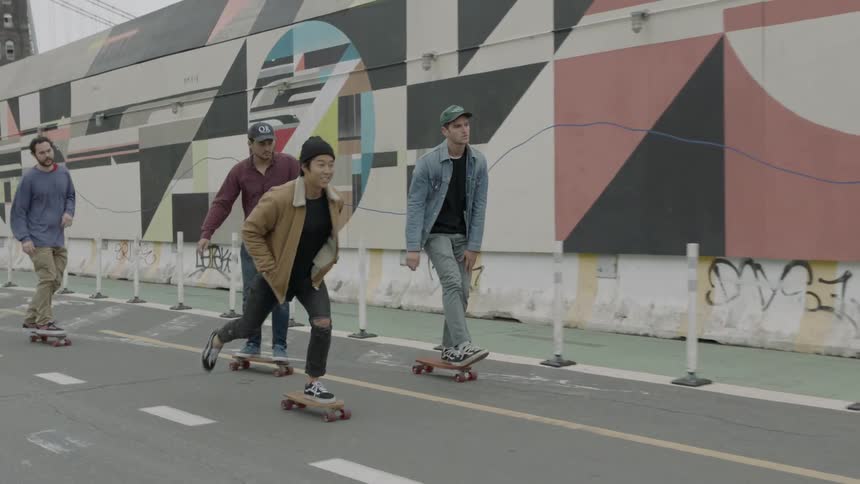 Several young adults skateboarding on a city street