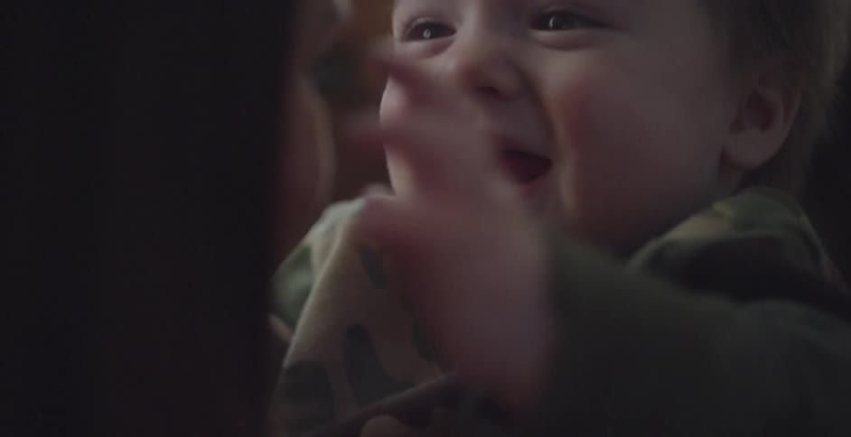 A baby laughs and touches a woman's face