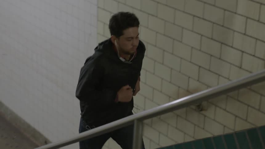A man wearing earbuds jogs up some subway stairs