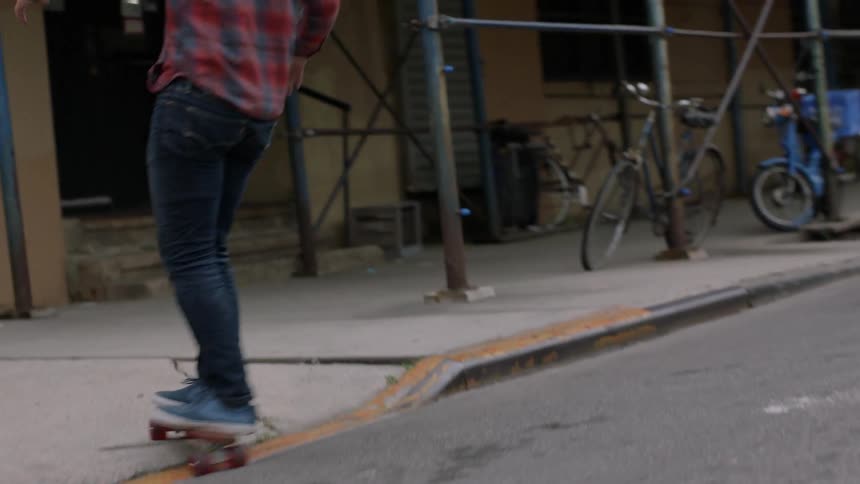 Young man's skateboarding on a city street and then moving onto the sidewalk