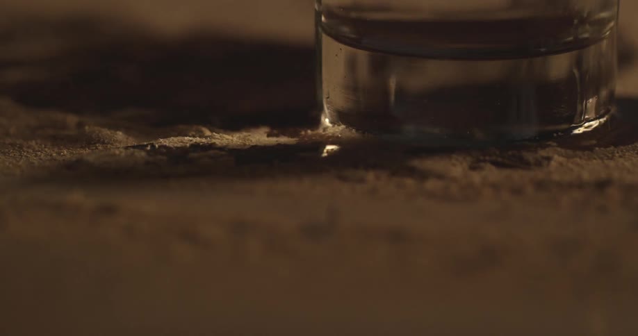 Close up of water pouring out of a glass near the base