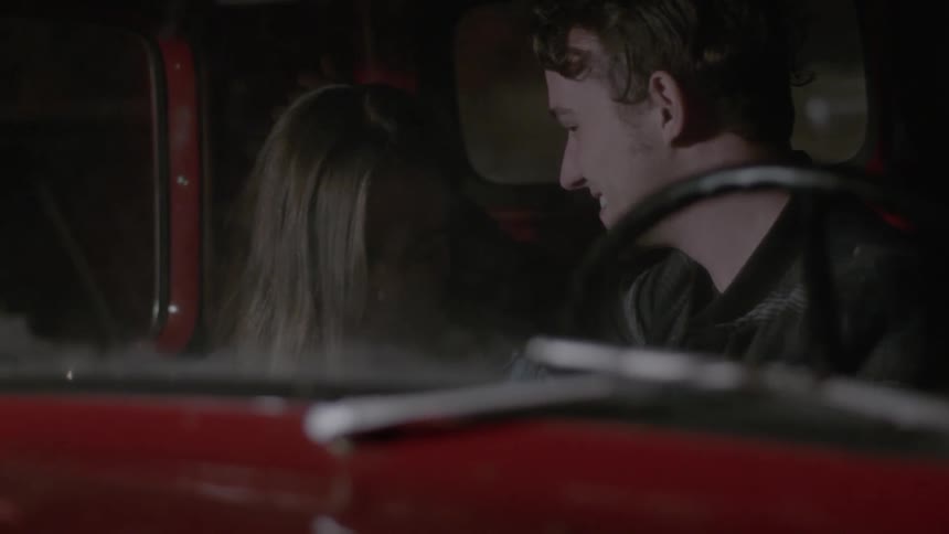 A man caresses a woman's hair in a car