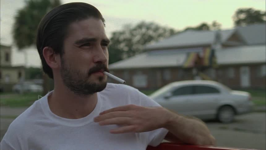 Person riding in the back of a pickup truck and attempting to light a cigarette under his shirt