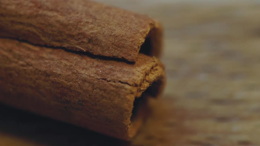 Cinnamon sticks rest on a wood counter