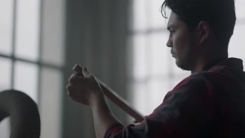 A man examines a board before shaving it on a tool
