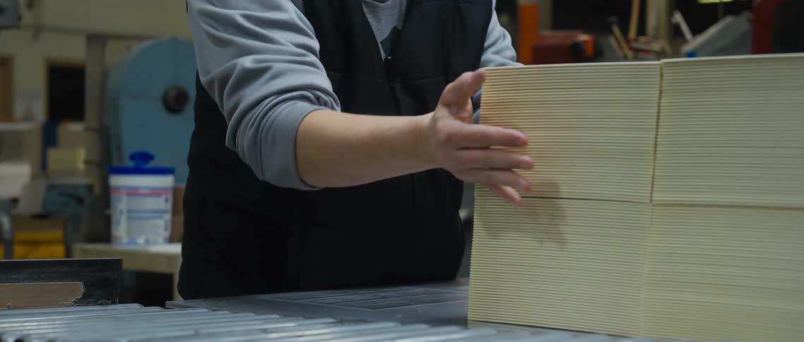 Warehouse worker puts sheets of white cardboard in a stack then carries two stacks to another location