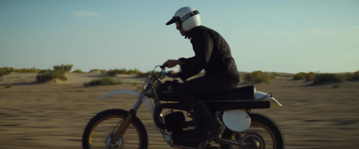 A cyclist wearing a helmet is riding a motorcycle through the desert