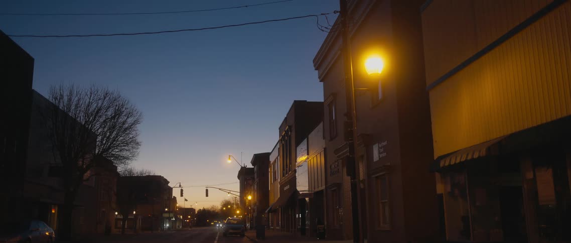 Town street with buildings being silhouetted against the sky at dusk