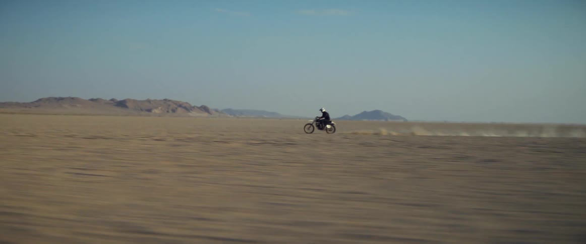 Motorcycle rider riding at high speed across the desert