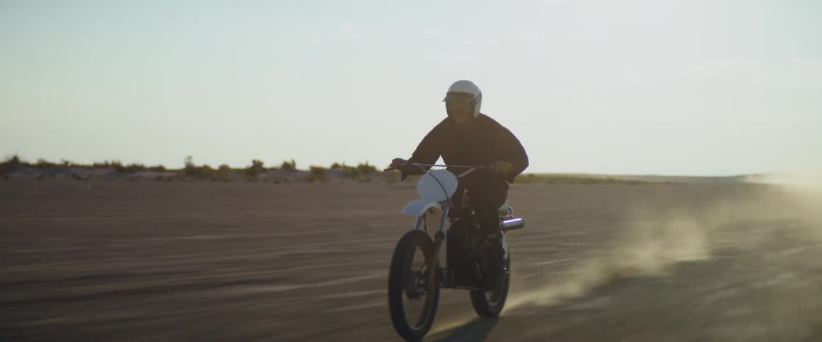 A cyclist wearing a helmet is riding a motorcycle across the desert