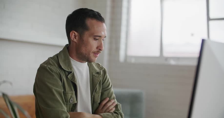 Anxious man looking at computer monitor then checking his cell phone