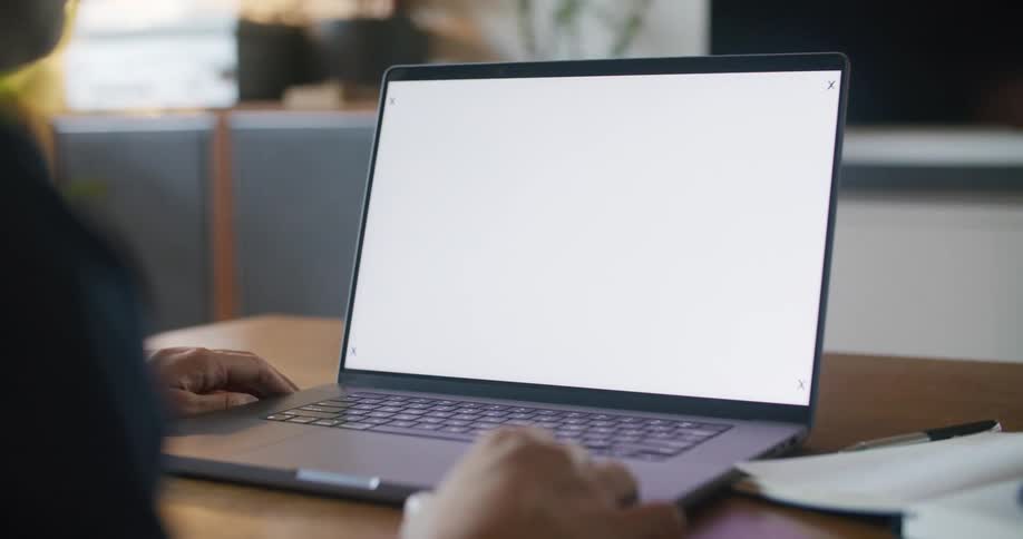 Someone is sitting in front of a laptop computer with a white screen