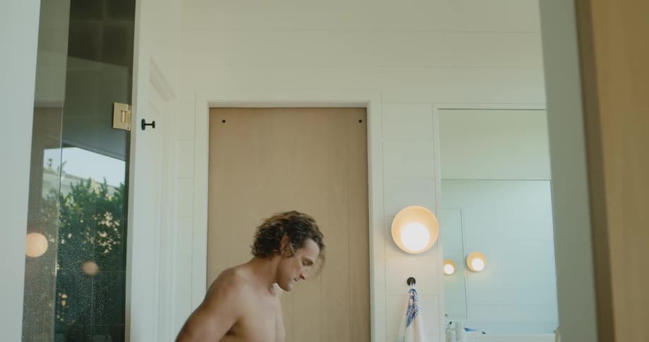 Shirtless man standing in the bathroom drying himself up with a towel