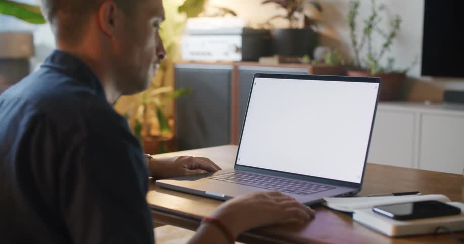 Man with blue shirt wristband and wristwatch uses laptop at table