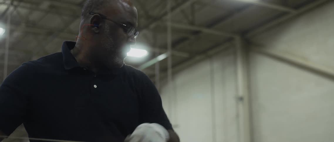 Bald male worker with glasses and naval blue polo shirt works in newspaper factory