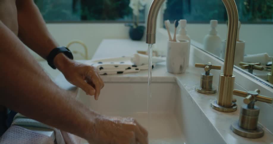 Man stands at sink shaving with safety razor